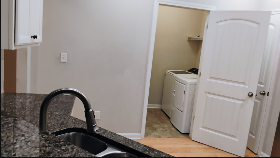 Clean kitchen with granite counters and tidy laundry room